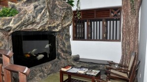 Un rincón interior acogedor con pared de piedra, chimenea y mobiliario de madera.