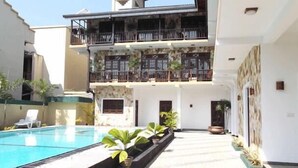 Un edificio de dos pisos con piscina, mobiliario exterior y un balcón.