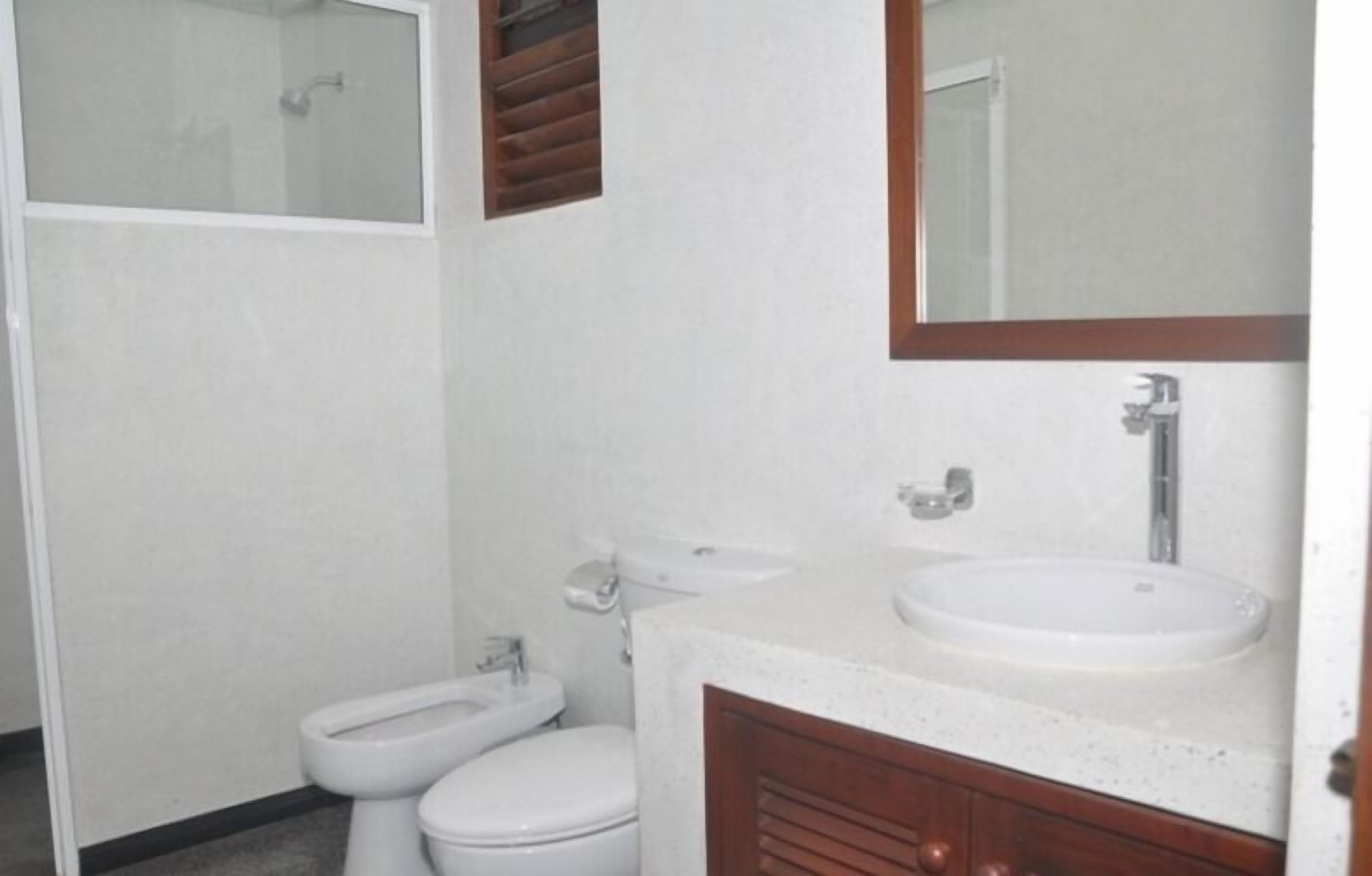 A bathroom with a toilet, sink, and mirror.