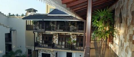 A multi-story building with balconies, a covered walkway, and potted plants.