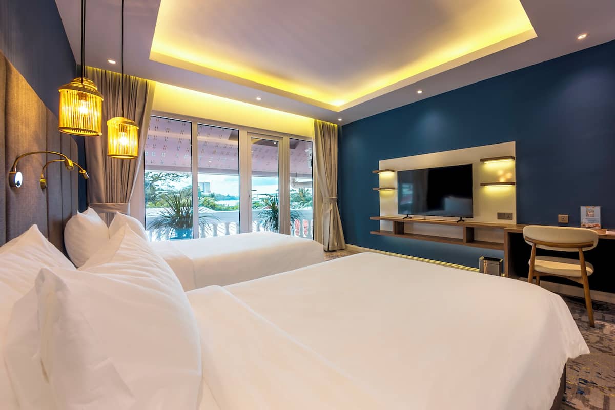 Ein Hotelzimmer mit zwei Betten, einem Schreibtisch, einem Fernseher und Blick ins Freie.