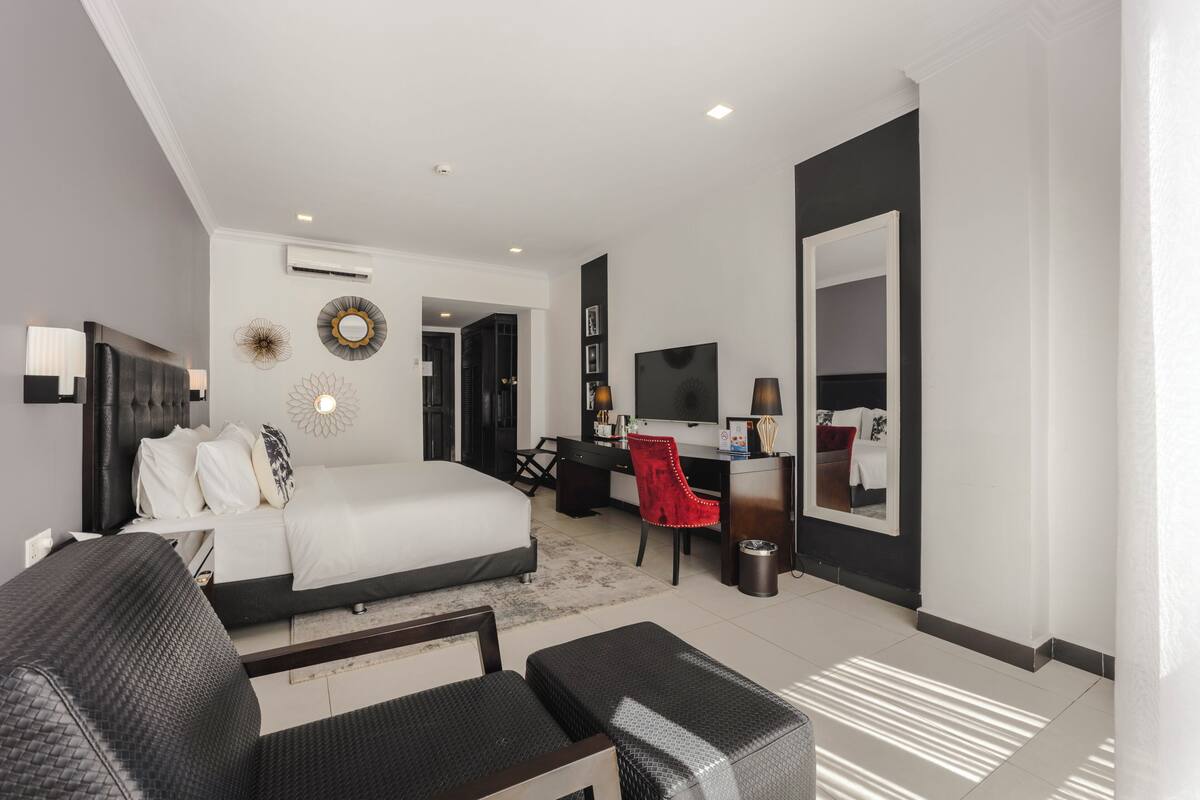 Ein modernes Hotelzimmer mit Bett, Schreibtisch, Stuhl und Fernseher.