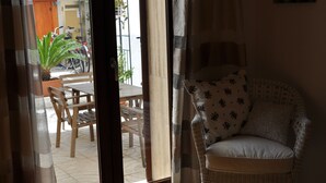 Une chaise en osier avec un coussin à motifs floraux, une table en bois et des chaises devant une porte.