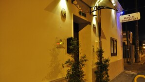 Un bâtiment avec une enseigne indiquant « chambre d’hôtes » et une plante en pot devant l’entrée.