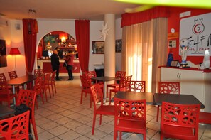Un restaurante con sillas y mesas rojas, una zona de bar y una decoración con una estrella blanca en la pared.