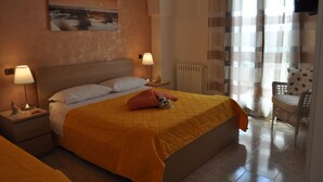 Une chambre d’hôtel avec un grand lit, deux tables de chevet avec des lampes, un radiateur, une chaise et un tableau au mur.