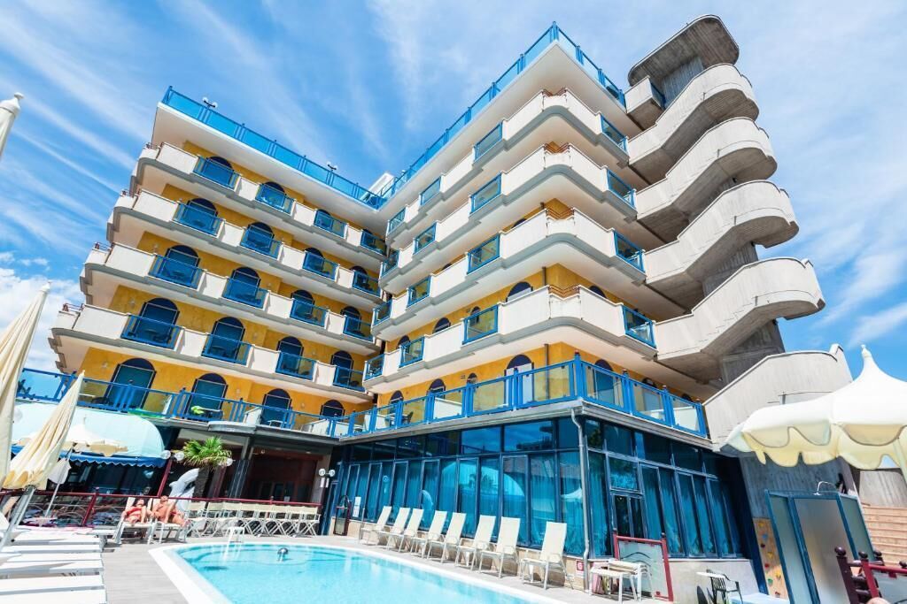 A multi-story hotel with a pool area, outdoor seating, and a distinctive architectural design.