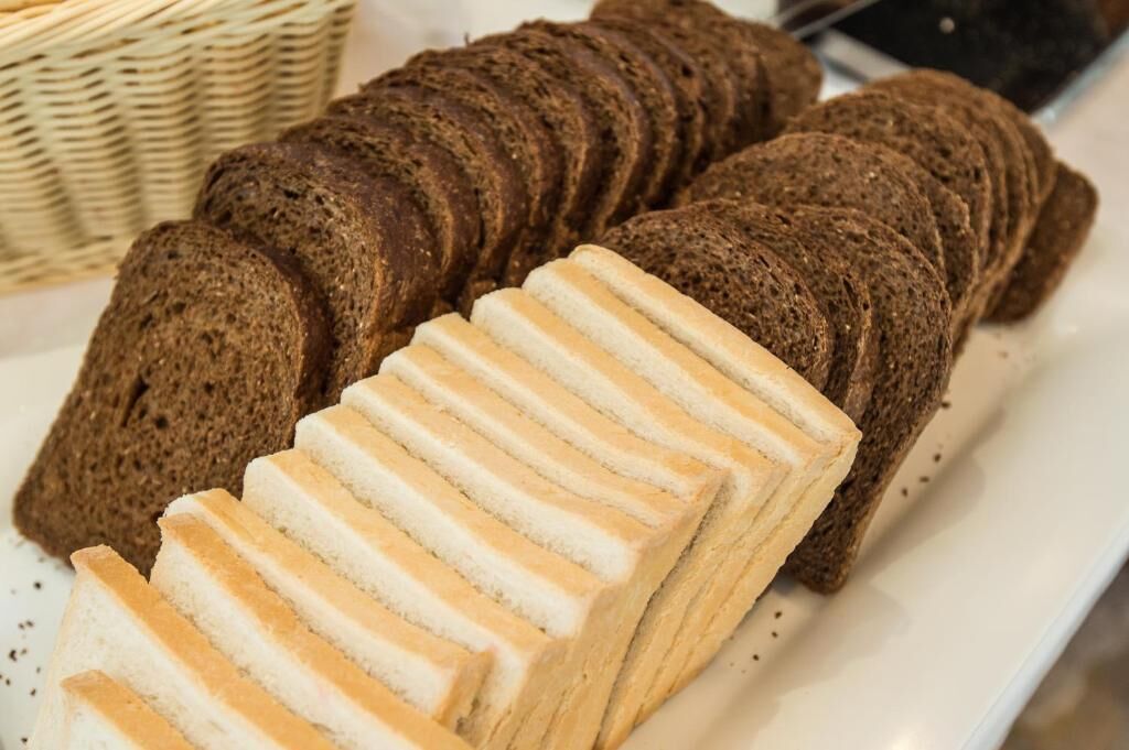 Dos panes, uno de centeno oscuro y otro de trigo blanco, cortados y colocados en un plato.