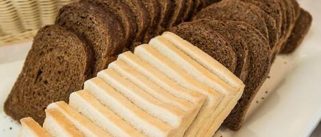 Dos panes, uno de centeno oscuro y otro de trigo blanco, cortados y colocados en un plato.