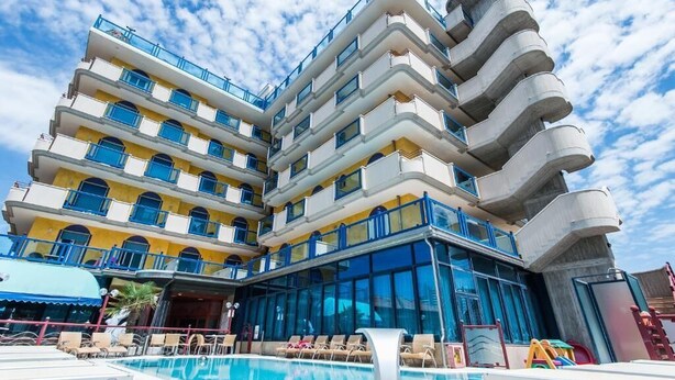 Un hotel de varios pisos con zona de piscina, balcones y un diseño arquitectónico distintivo.