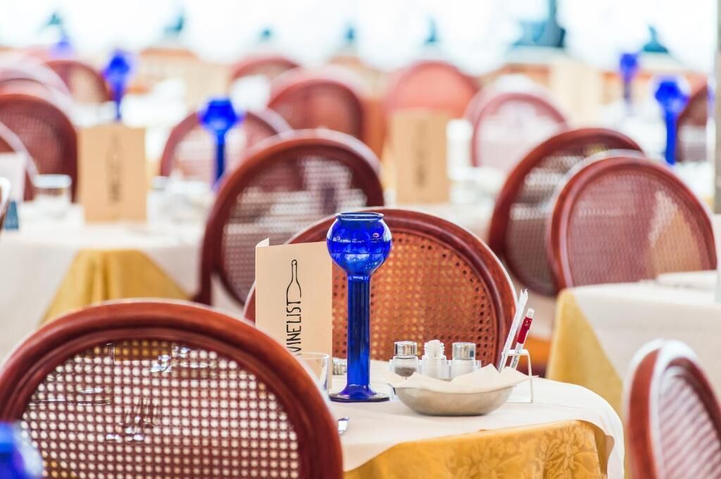A restaurant setting with multiple tables, each with a menu stand and a blue glass.