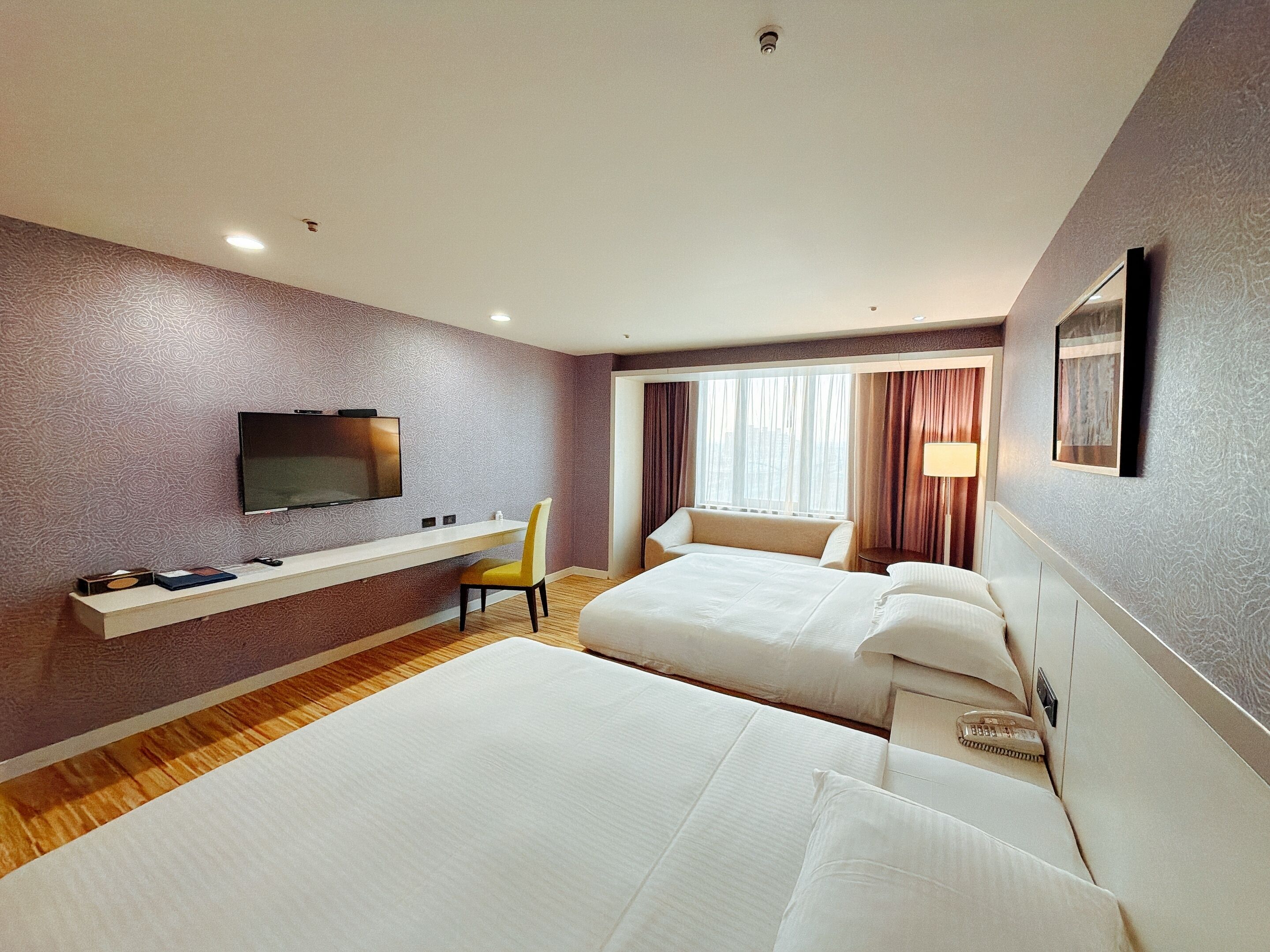 A hotel room with two beds, a TV, a desk, and a chair.
