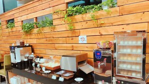 A buffet setup with a coffee machine, tea station, and a variety of food items. - WeMeet Hotel (Pingtung)