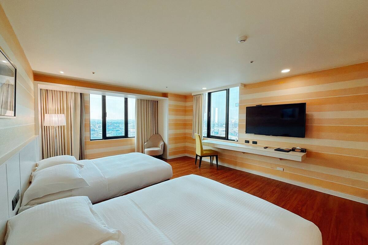 Una habitación de hotel con dos camas, televisión, escritorio y una silla.