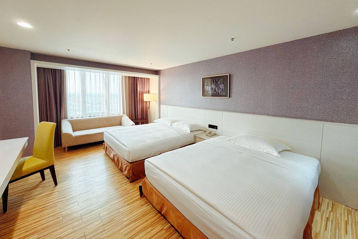 Una habitación de hotel con dos camas, un sofá, un escritorio y una silla.