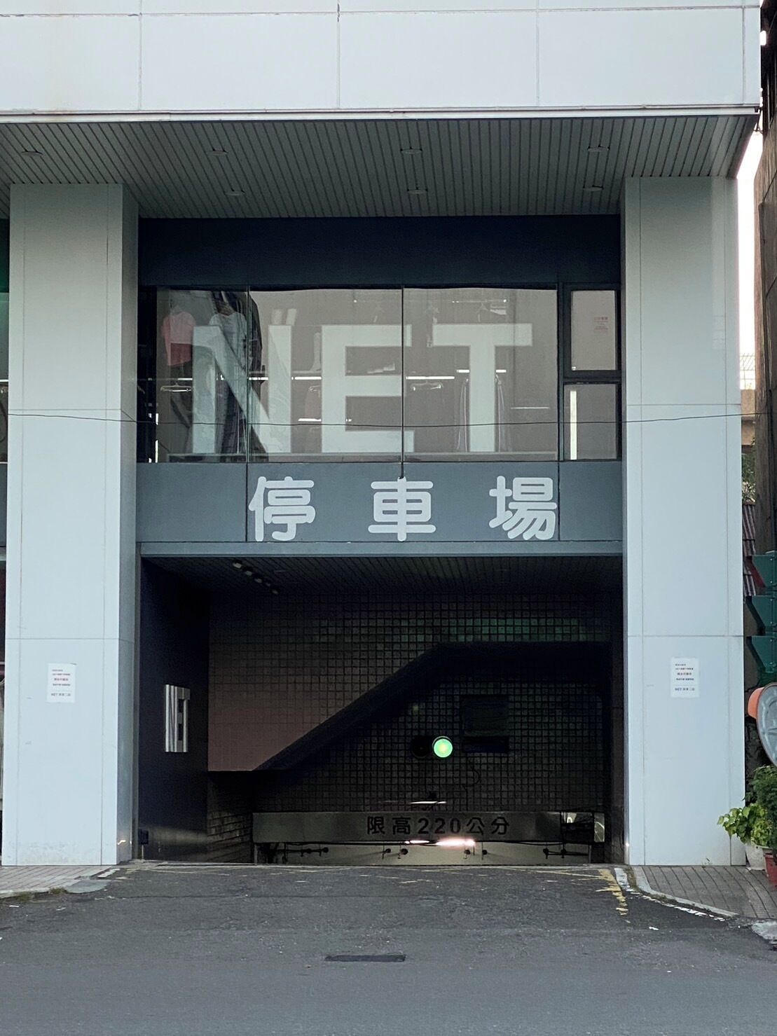 Entrada de un edificio con un cartel que dice "NET" y "停车场", indicando un área de estacionamiento.