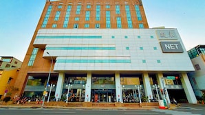 A modern building with a prominent NET sign, featuring a multi-story structure with large windows and a flat roof. - WeMeet Hotel (Pingtung)