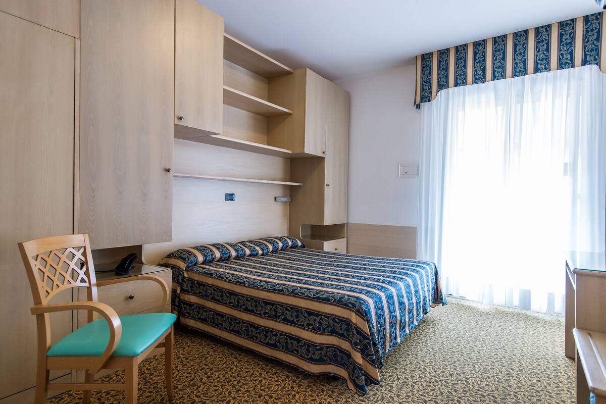 A hotel room with a bed, a desk, and a chair.