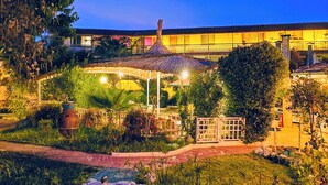A well-lit garden area with a gazebo, a pathway, and a building in the background. - Erendiz Garden Hotel (Kemer)