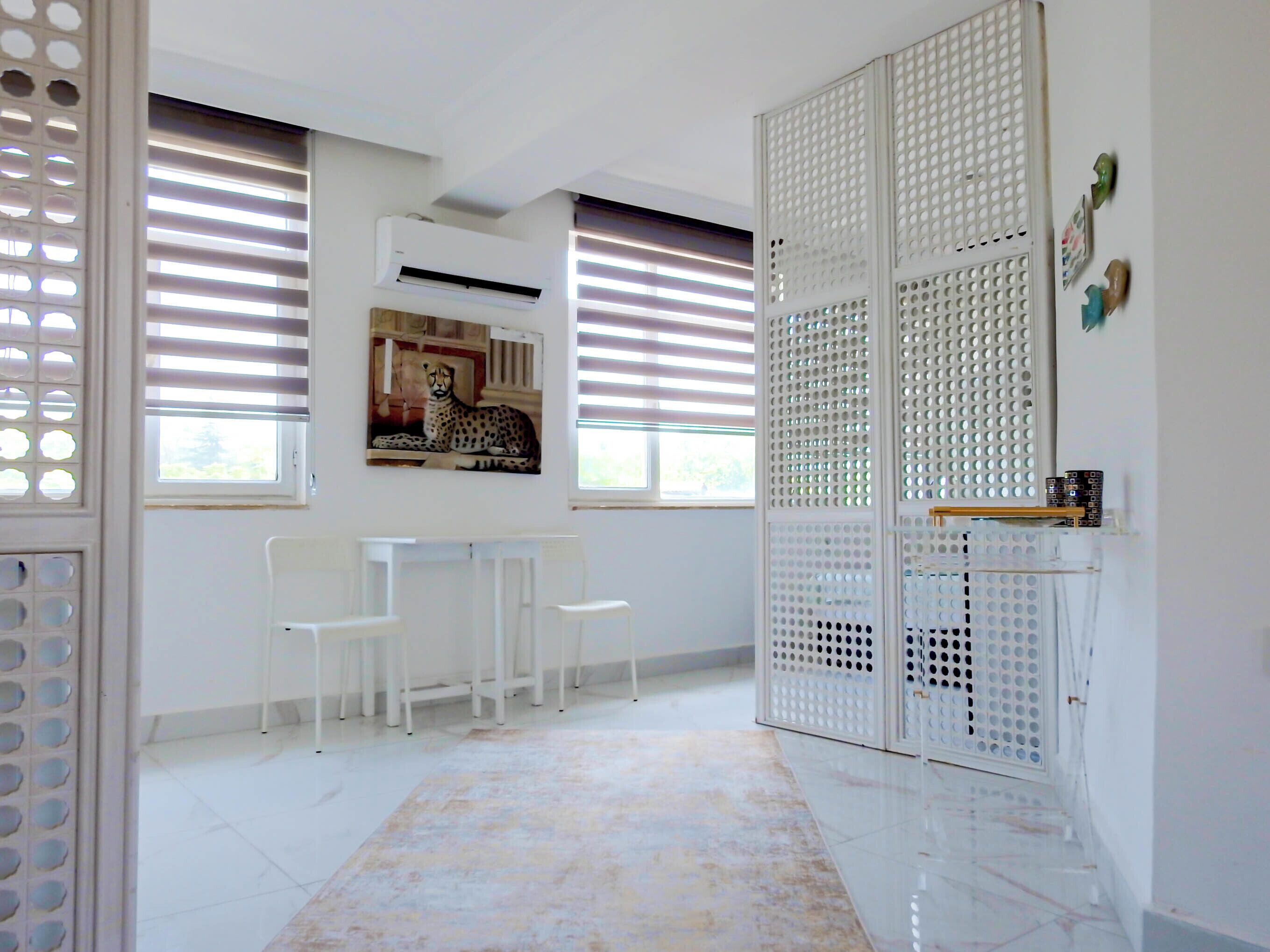 A hallway with white chairs, a radiator, and a leopard painting on the wall.