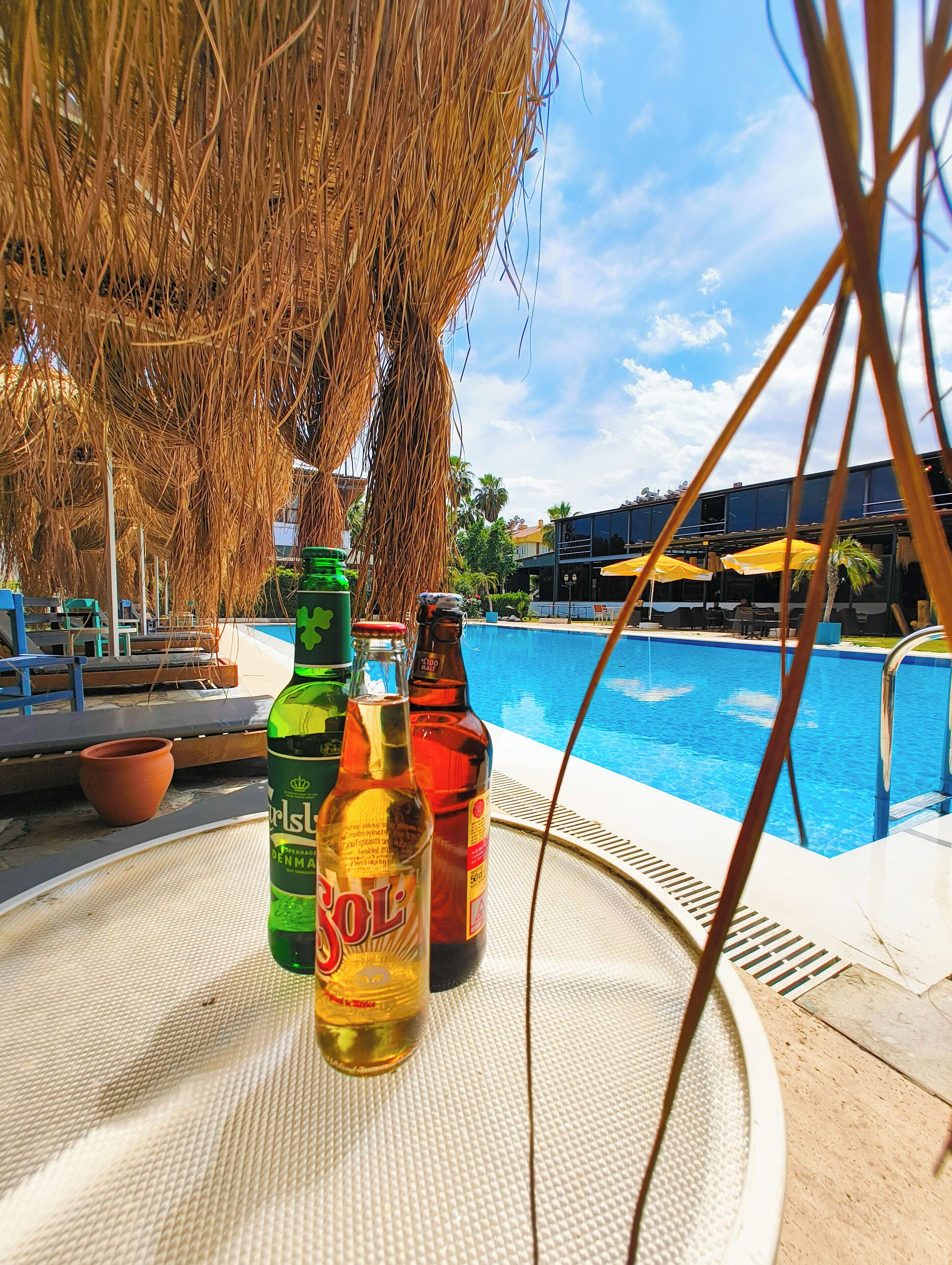 Área da piscina com mesa, garrafas e vista para a piscina.