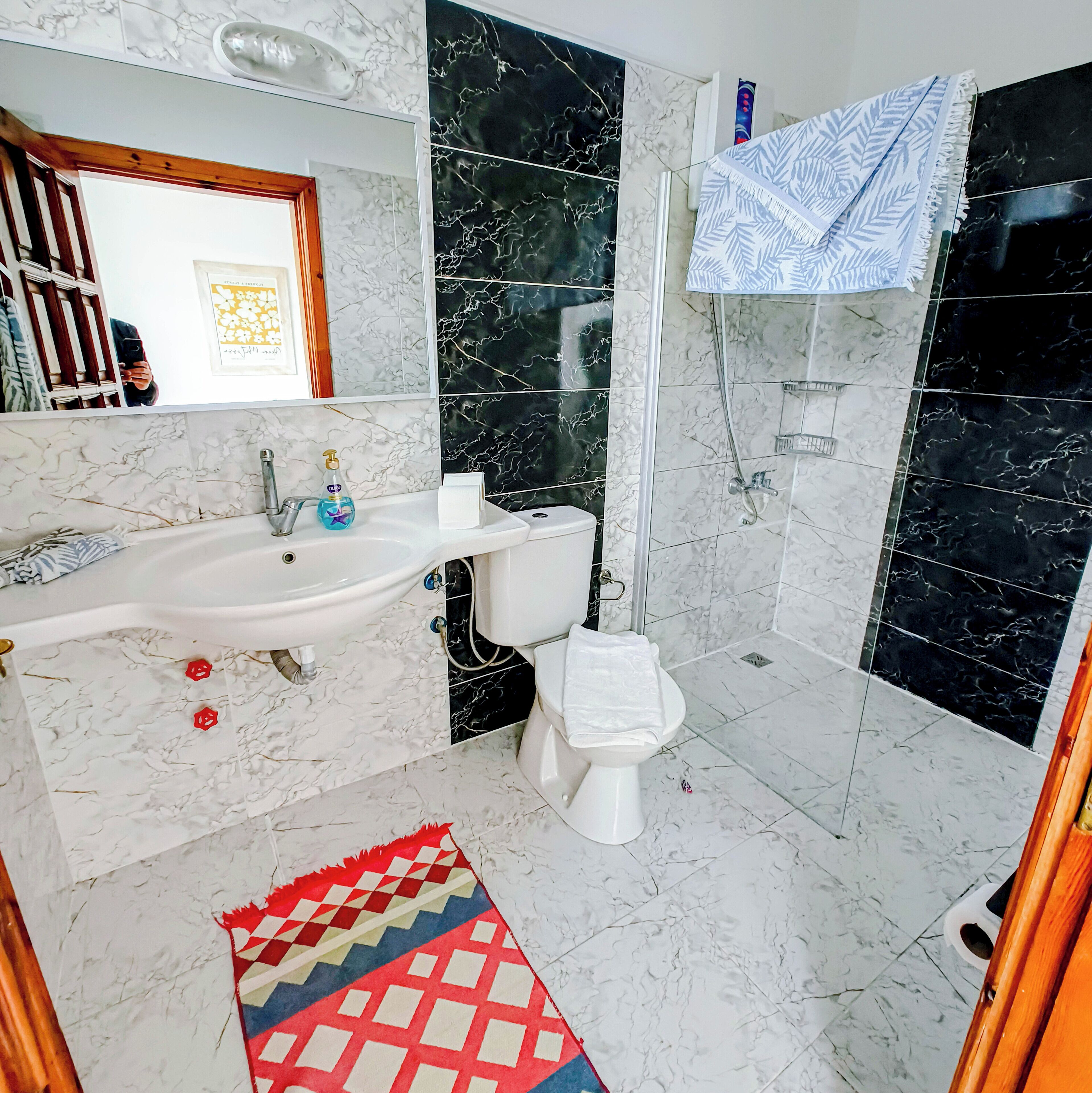 A bathroom with a white sink, a toilet, and a shower area.