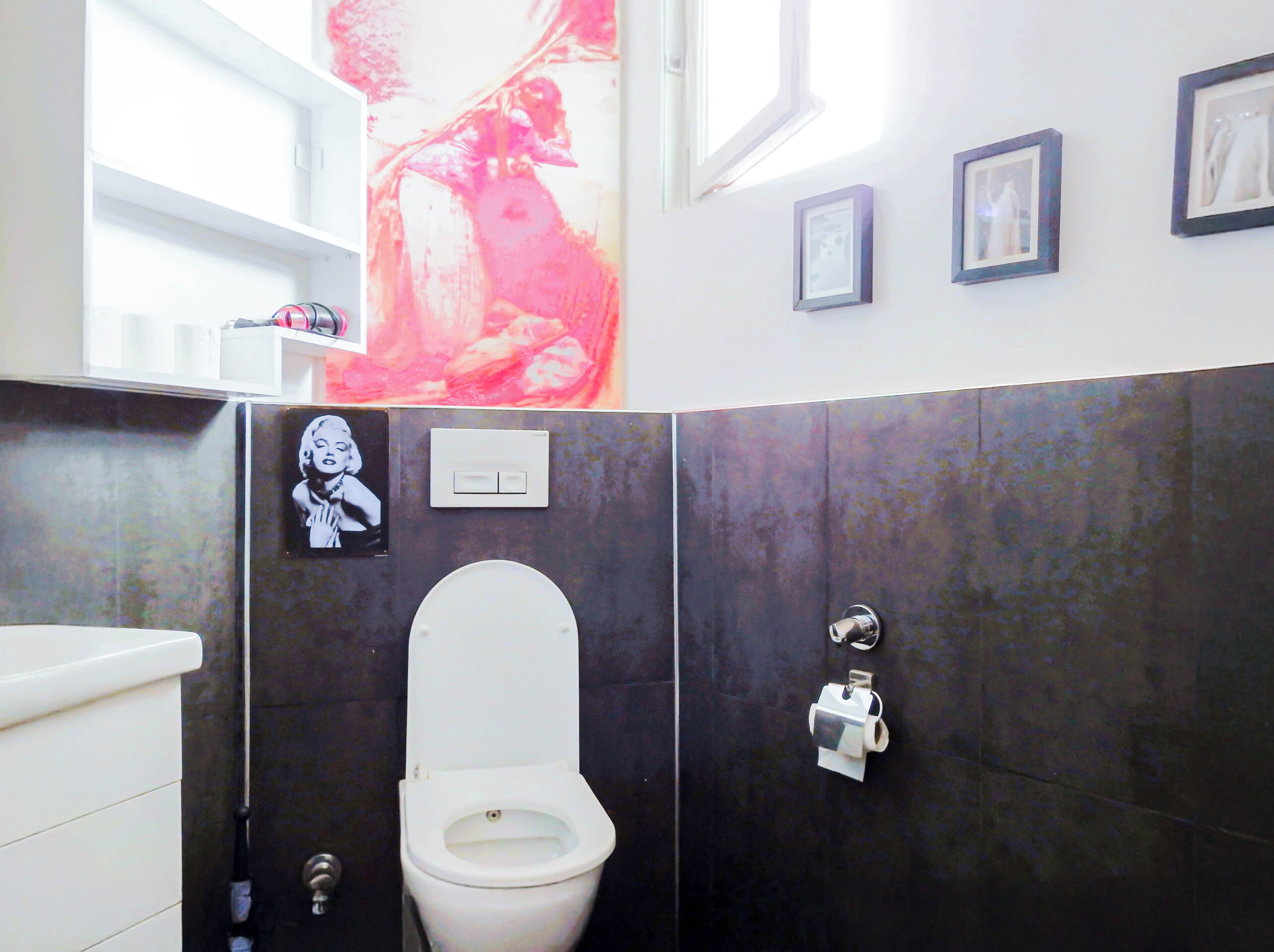 A bathroom with a toilet, a sink, a shower, and a large window.
