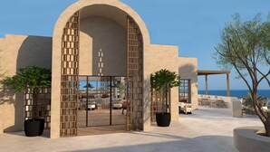 A modern building with a large arched entrance, outdoor seating area with tables and chairs, and a view of the sea. - Nana Royal Premium Resort & Spa (Hersonissos)