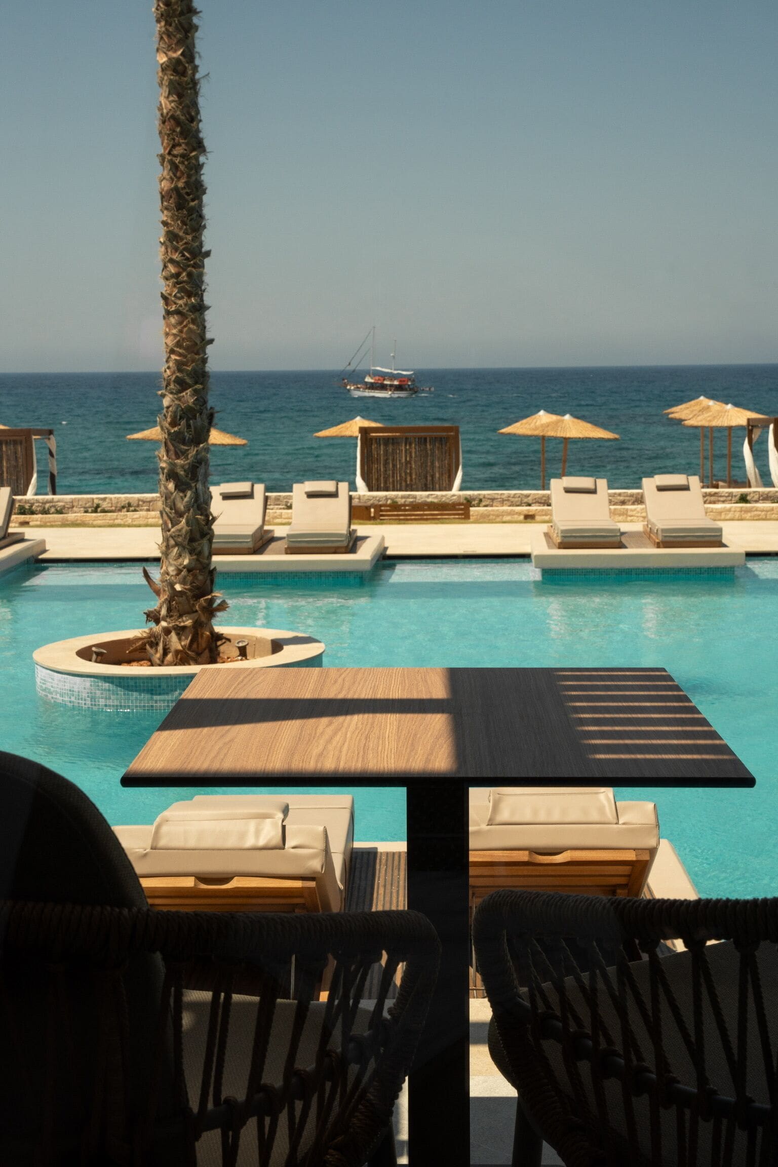 Un espace aménagé au bord de la piscine, avec des chaises longues, des parasols et une vue sur la mer.