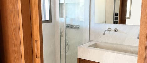 A modern bathroom with a glass-enclosed shower, a sink with a wooden vanity, and a mirror.