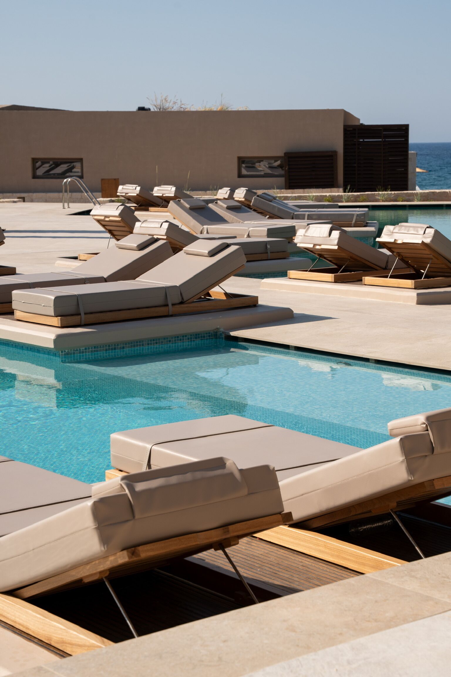 A poolside area with lounge chairs and a view of the ocean.
