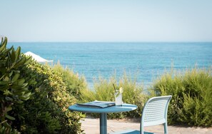 A table with a drink and a menu, overlooking a body of water. - Canvas by Mitsis Cretan Village (Hersonissos)