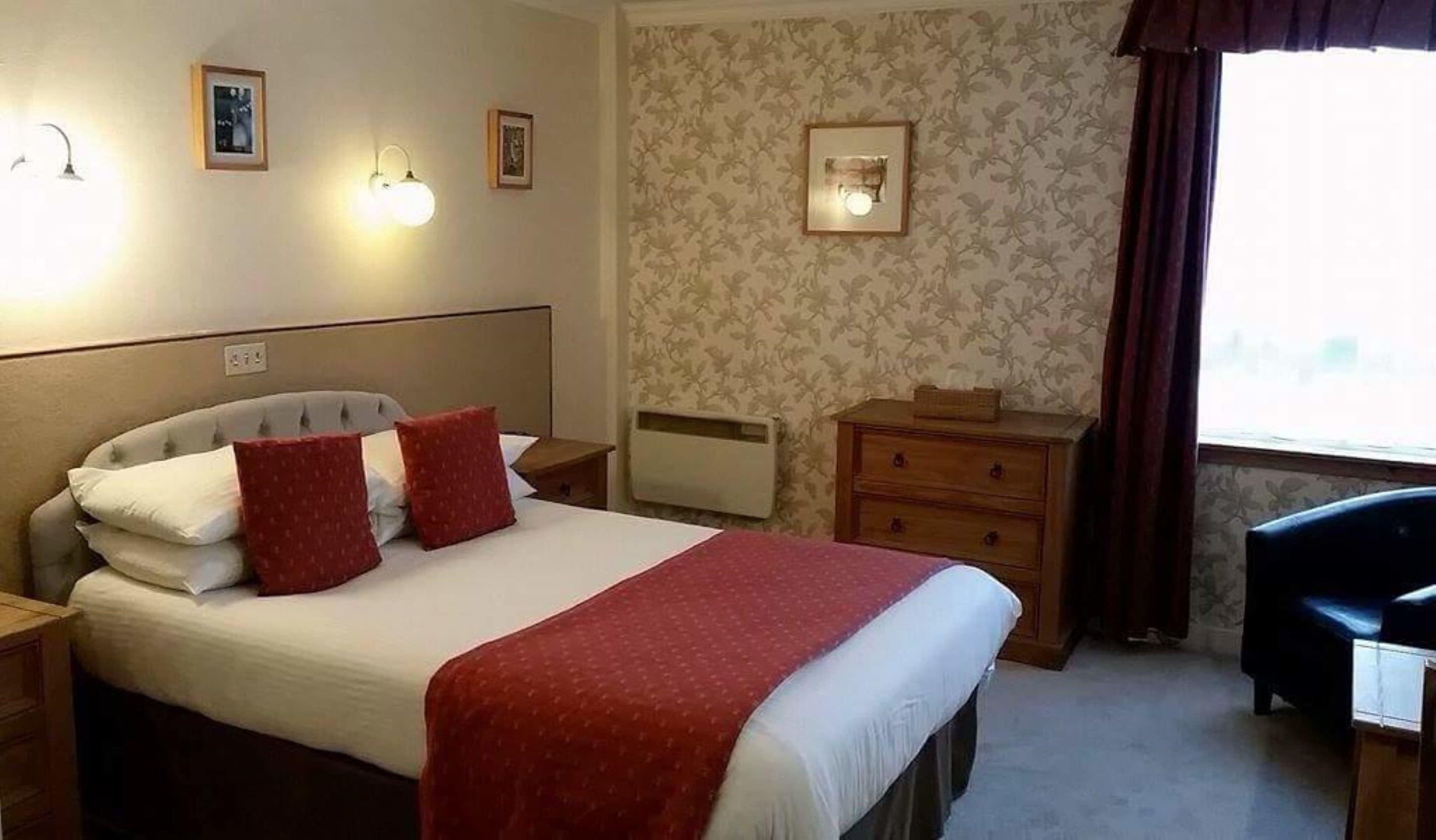 Ein Hotelzimmer mit einem Bett, zwei Nachttischen, einem Schminktisch und einem Sessel.
