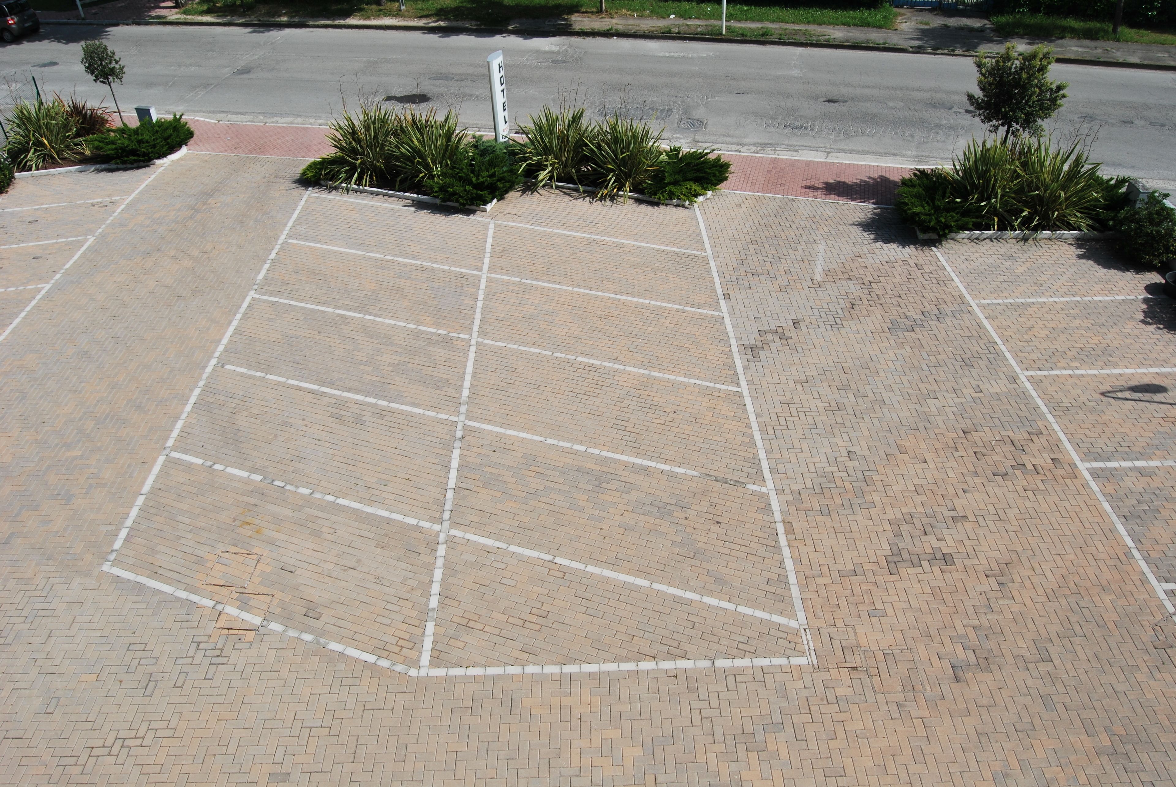 Um estacionamento com vagas demarcadas e um letreiro de hotel ao fundo.
