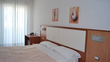 Une chambre d’hôtel avec un grand lit, une table de chevet en bois, un bureau et deux tableaux au mur.