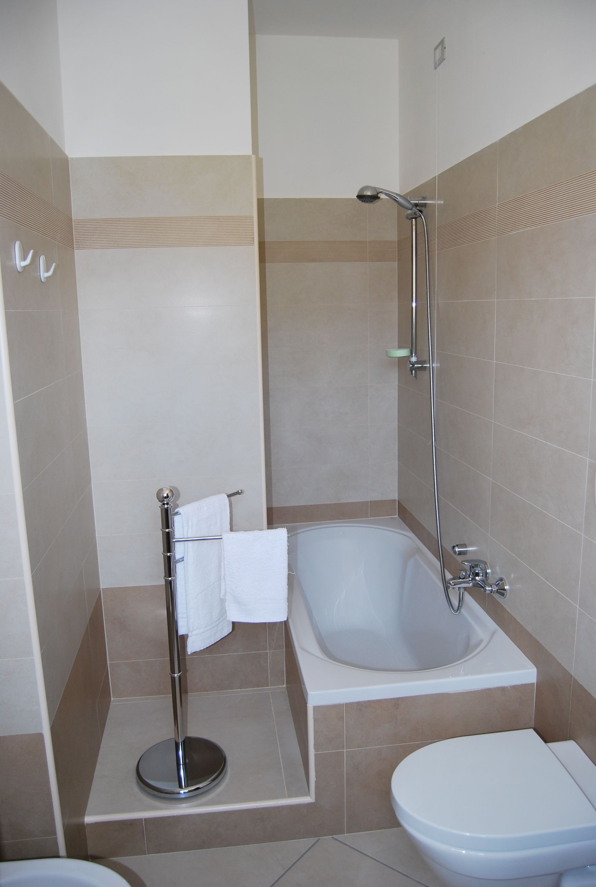 Een badkamer met een bad, toilet en douche.