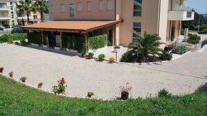 Un hotel con una zona de estar exterior cubierta, un patio empedrado y plantas en macetas.