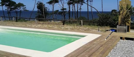 Una piscina al aire libre de temporada, sombrillas