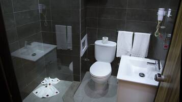 Une salle de bain avec des toilettes, un lavabo et une douche.