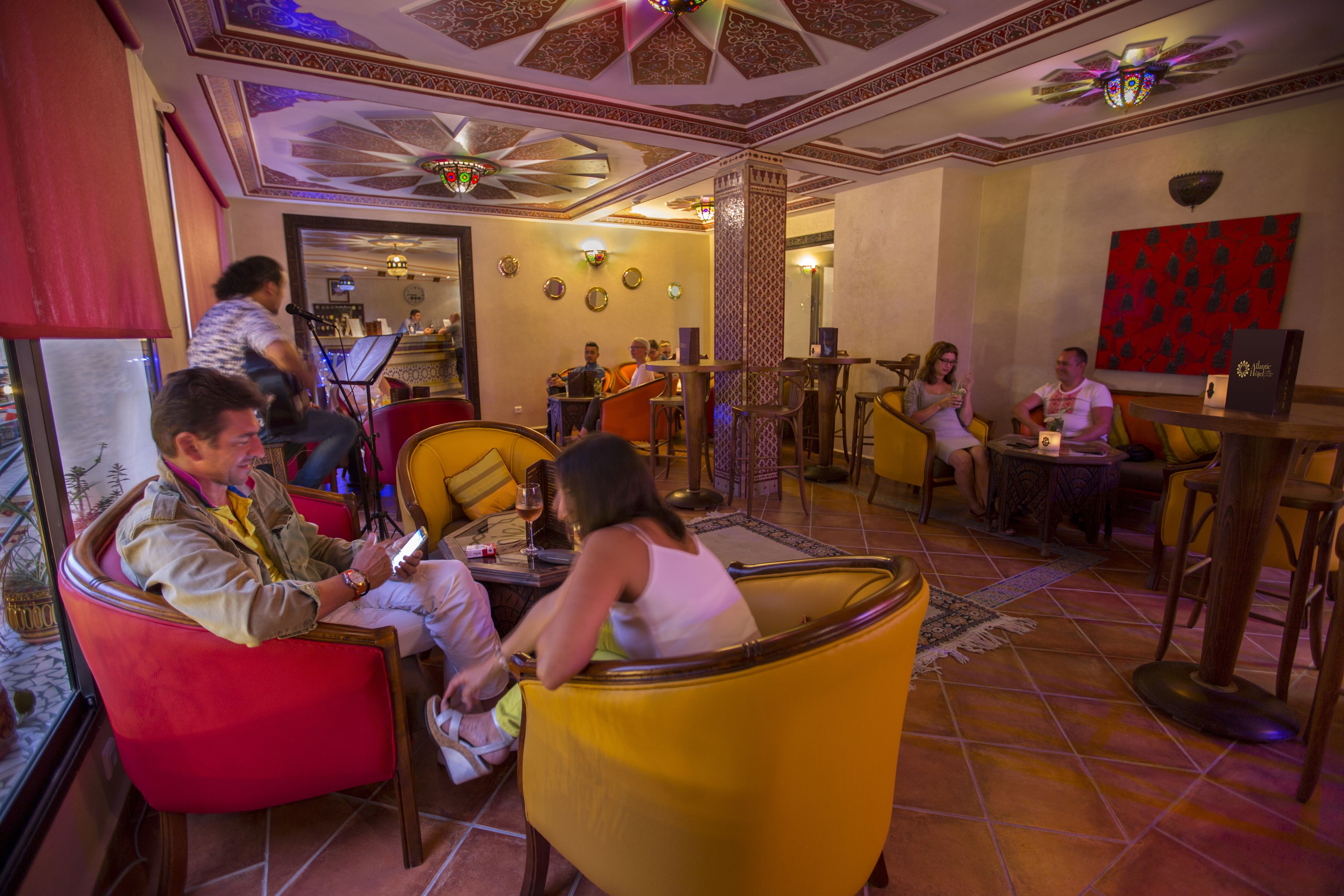 A lobby with red and yellow seating, a piano, and a bar area.