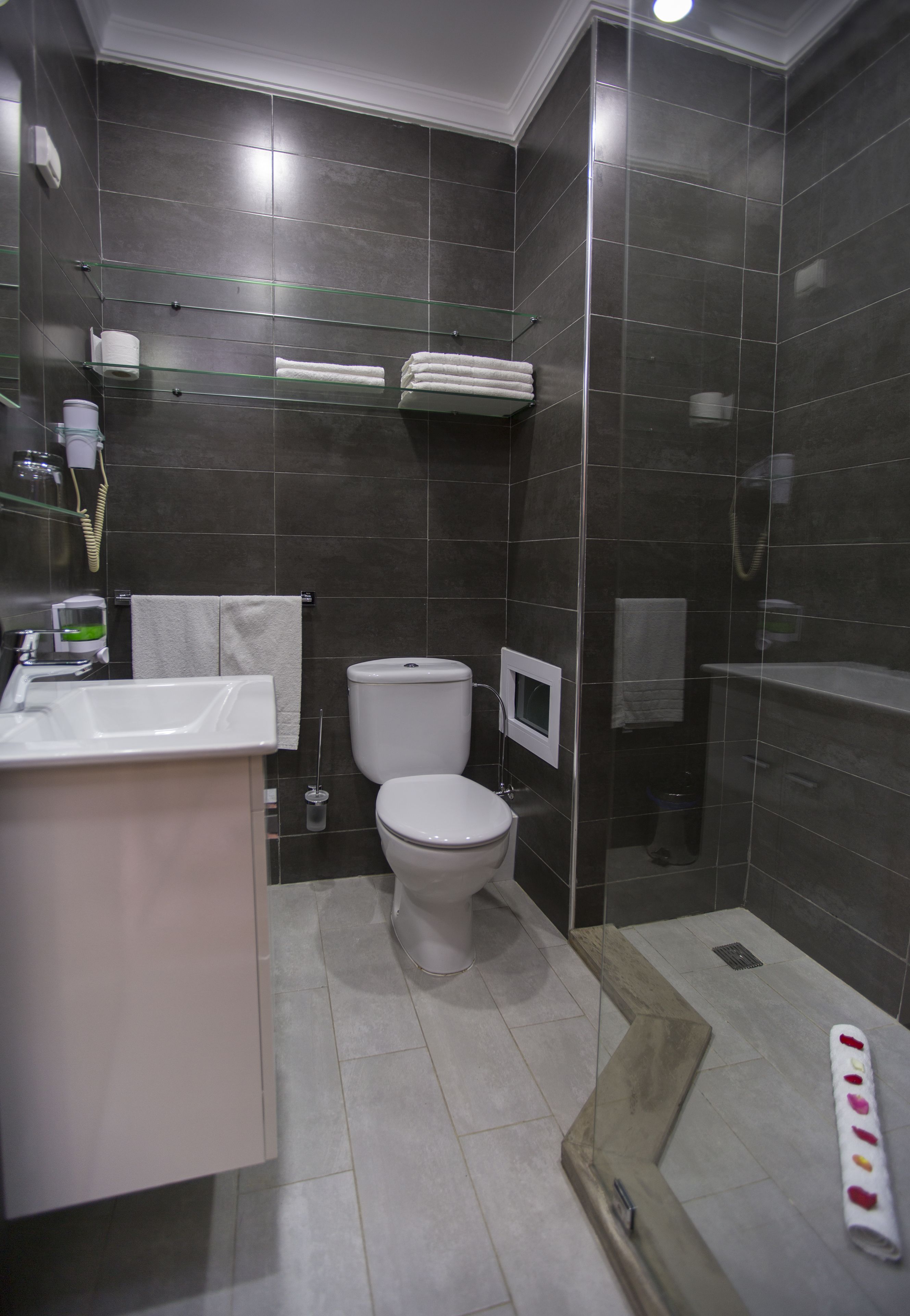 Un baño moderno con lavamanos blanco, inodoro y cabina de ducha con mampara de vidrio.