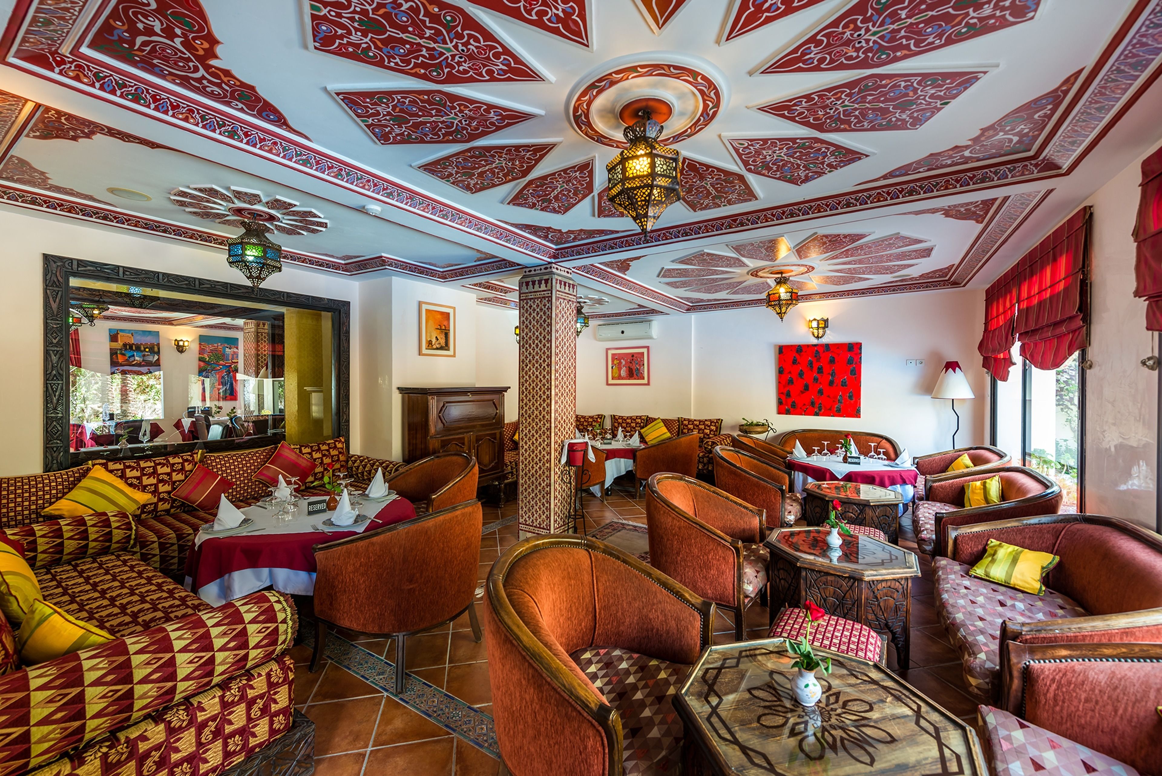 Un restaurante con elaborados diseños en el techo, asientos acolchados y una columna central.