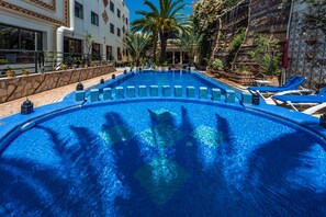 A large, clear swimming pool with blue tiles, surrounded by lounge chairs and palm trees. - Atlantic Hotel Agadir (Agadir)