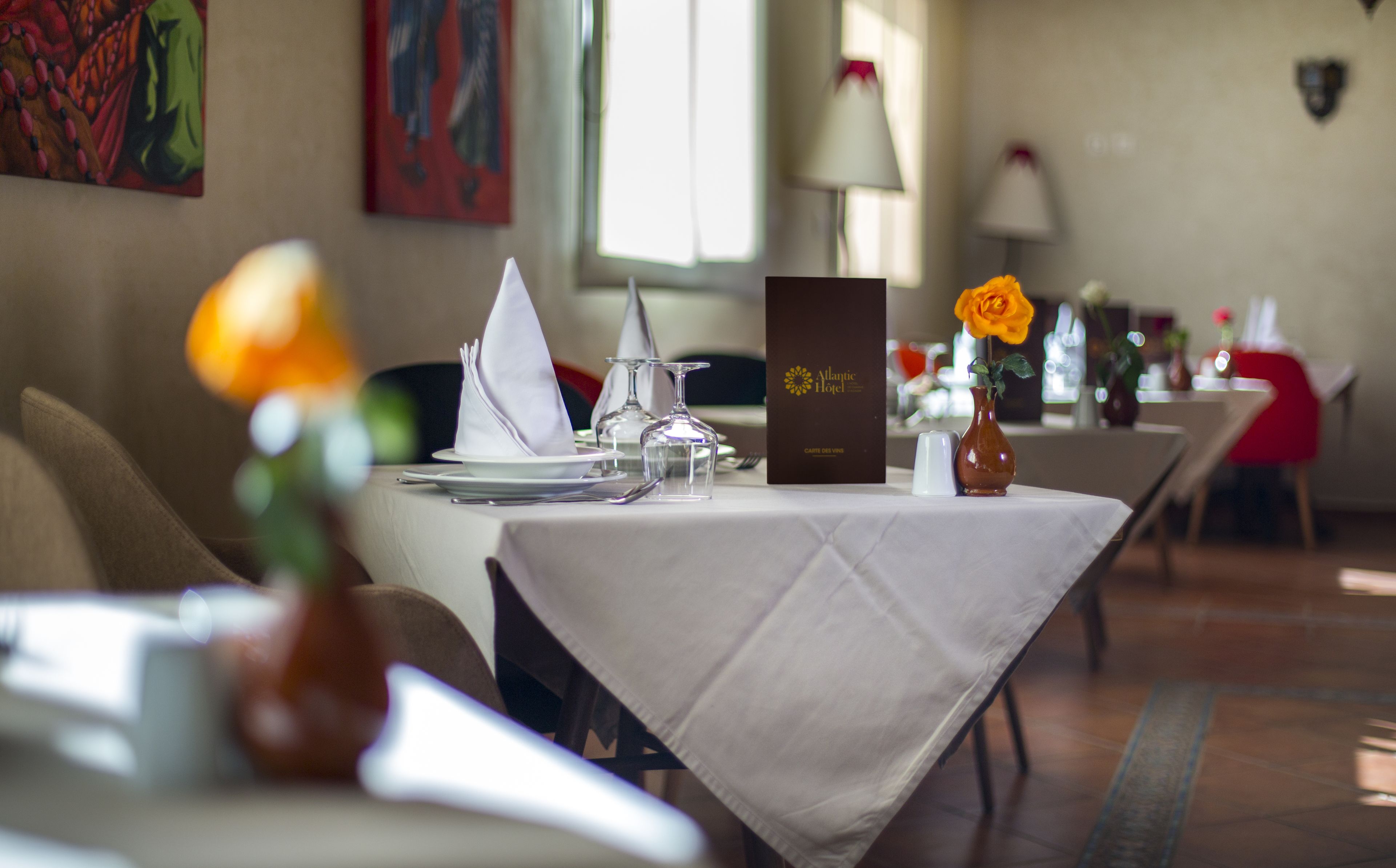 A dining table set with plates, glasses, and a menu at the Atlantic Hotel.