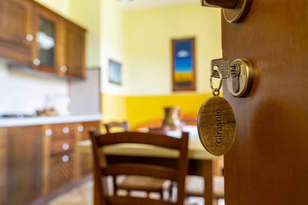 A kitchen with wooden cabinets, a chair, and a door with a key and a metal plate labeled "Girasole".