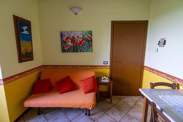 A room with a sofa, a small table, a door, and a wall with two paintings.