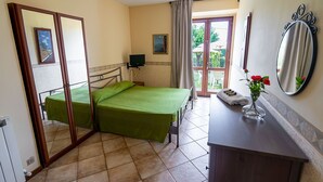 Ein Hotelzimmer mit zwei Betten, einem kleinen Schreibtisch, einem Spiegel und Blick ins Freie.