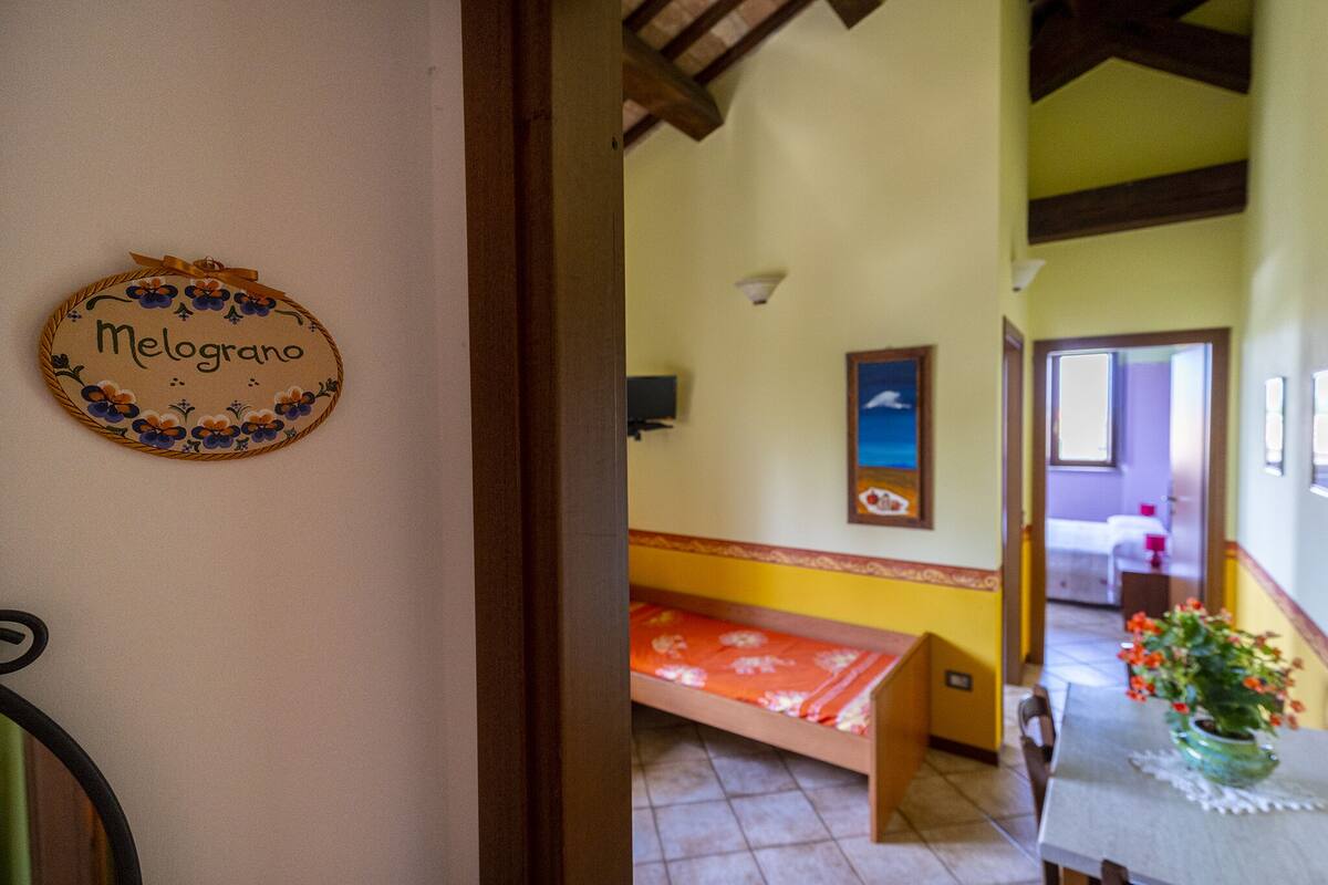 A room with a bed, a table with a vase, and a wall with a decorative plate.