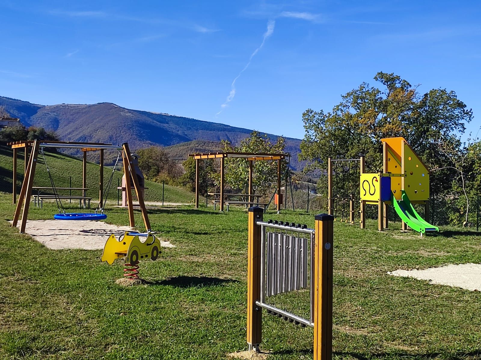 Un'area giochi all'aperto con altalene, scivoli e strutture per arrampicata.