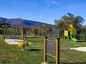 Un espace de jeux extérieur avec des balançoires, des toboggans et des structures d’escalade.